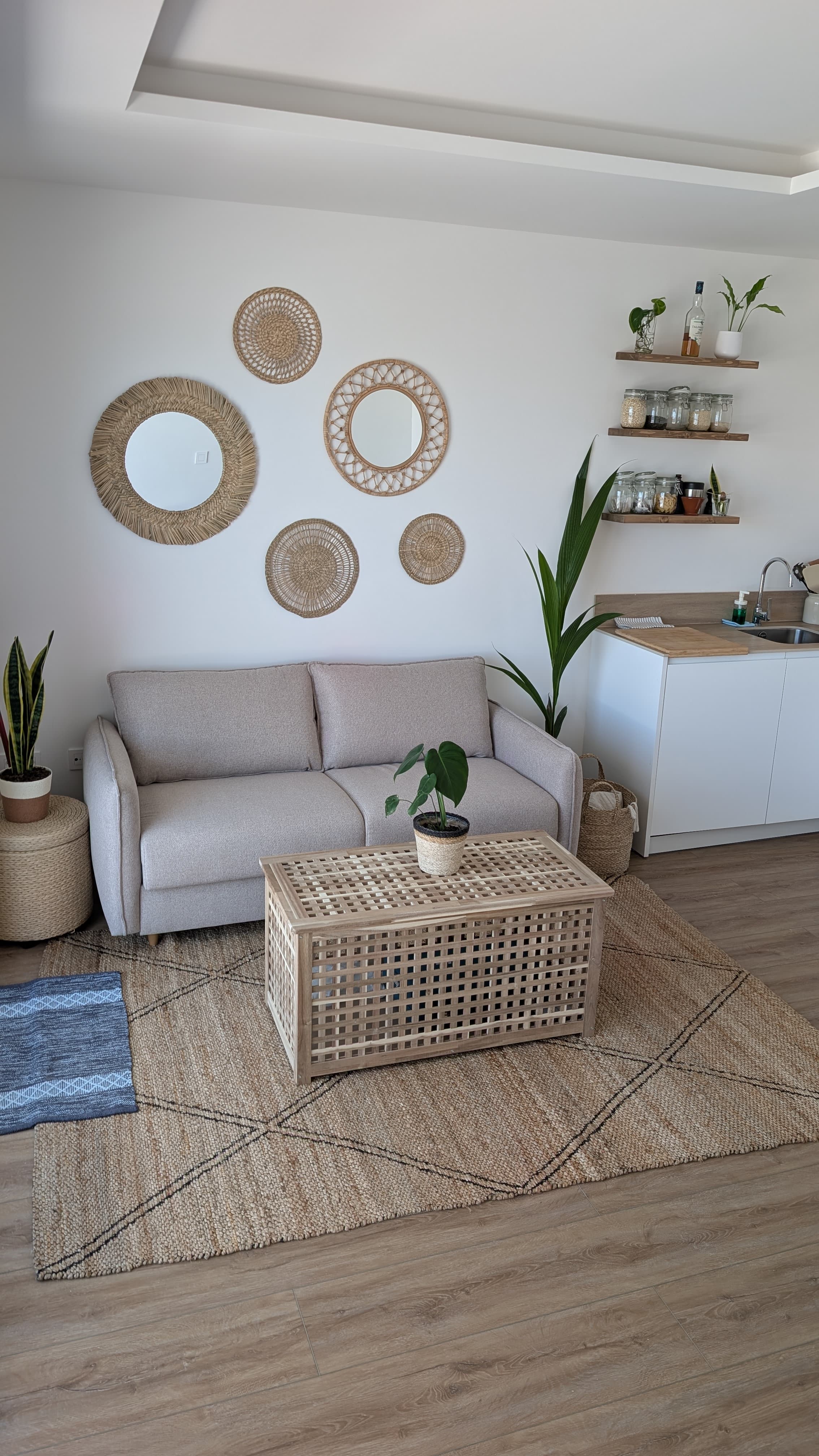 Open-plan living room with rattan mirrors and plants