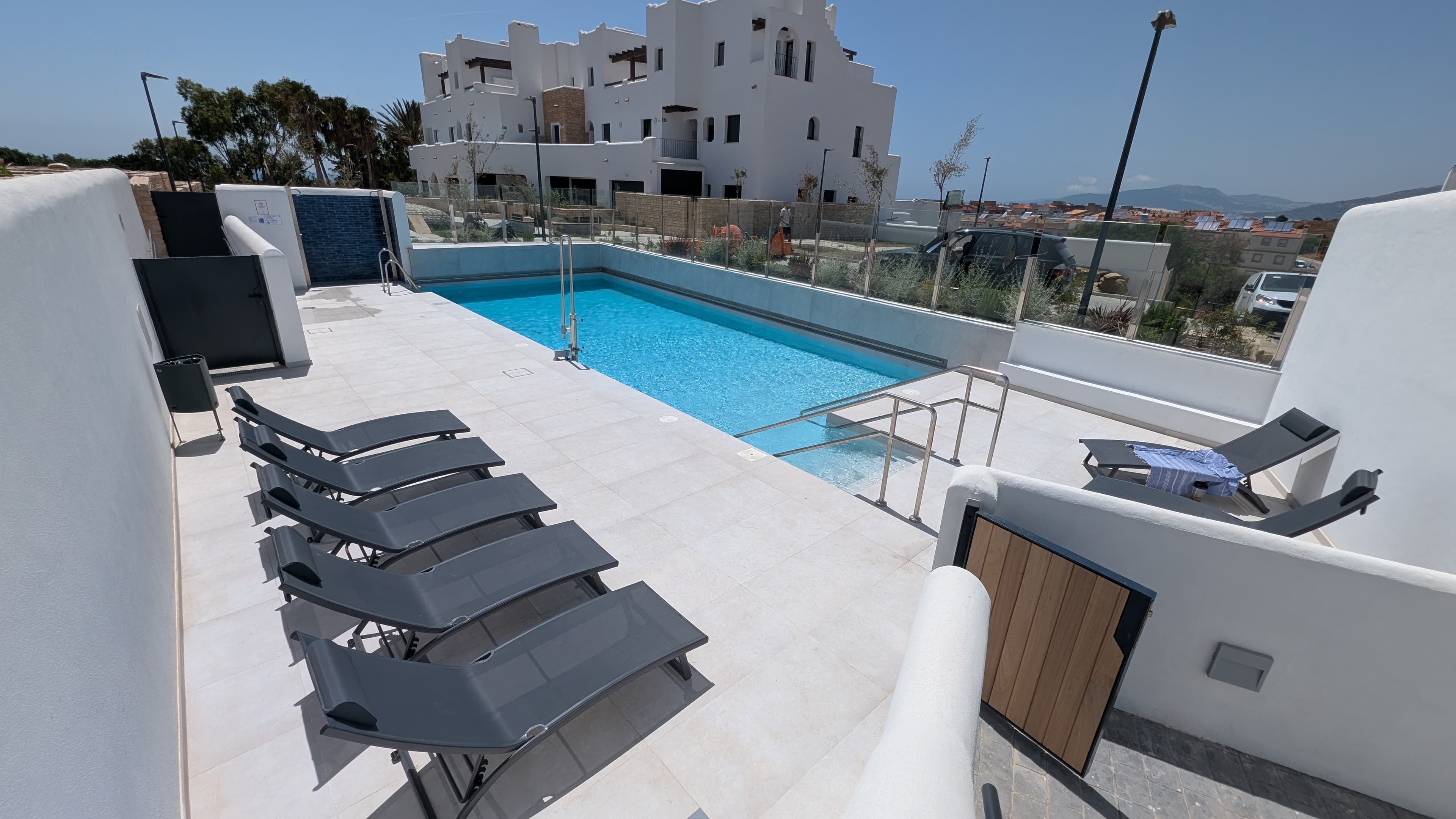 Community pool with sun loungers and view of the development