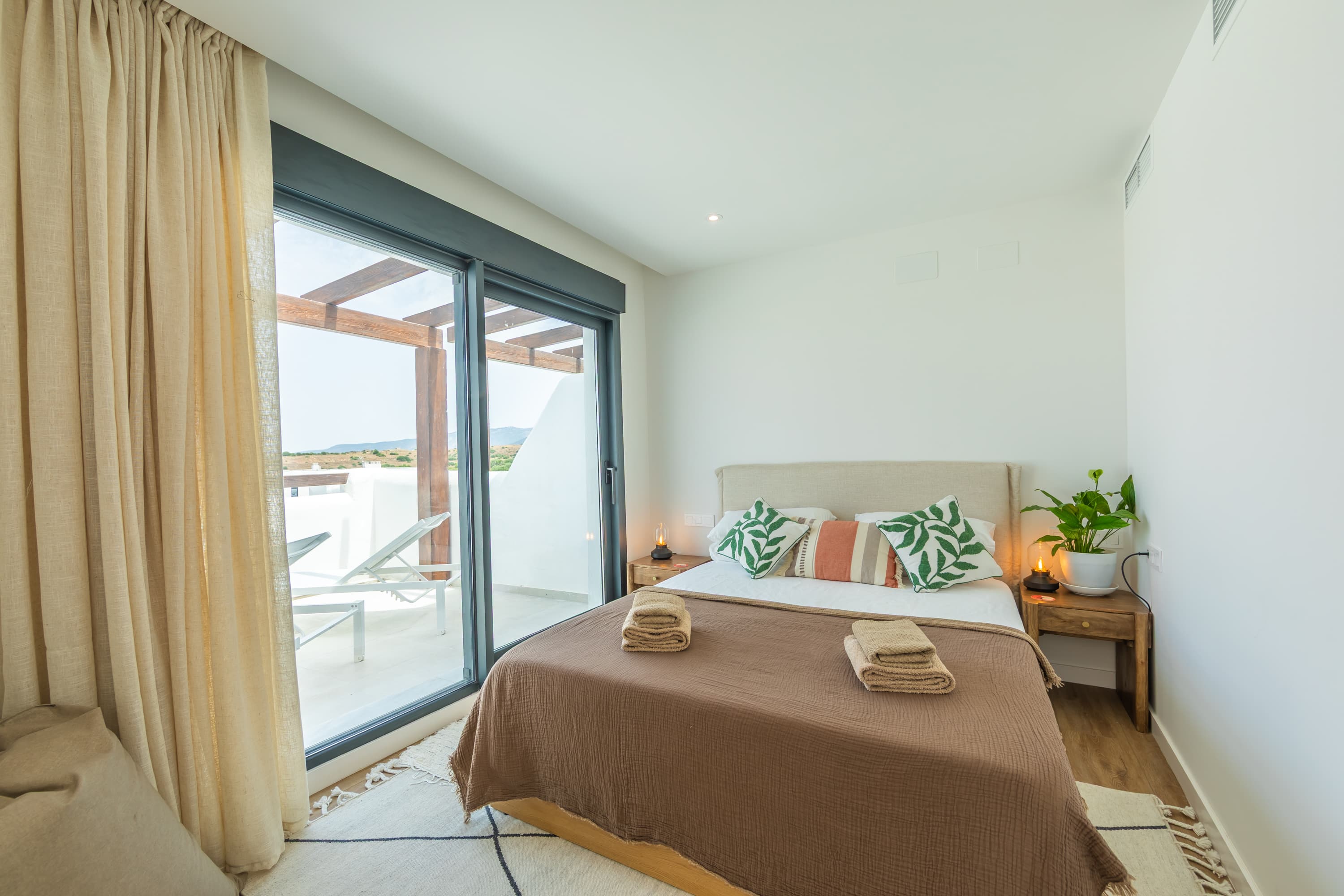 Master bedroom with double bed, brown throw, and green cushions