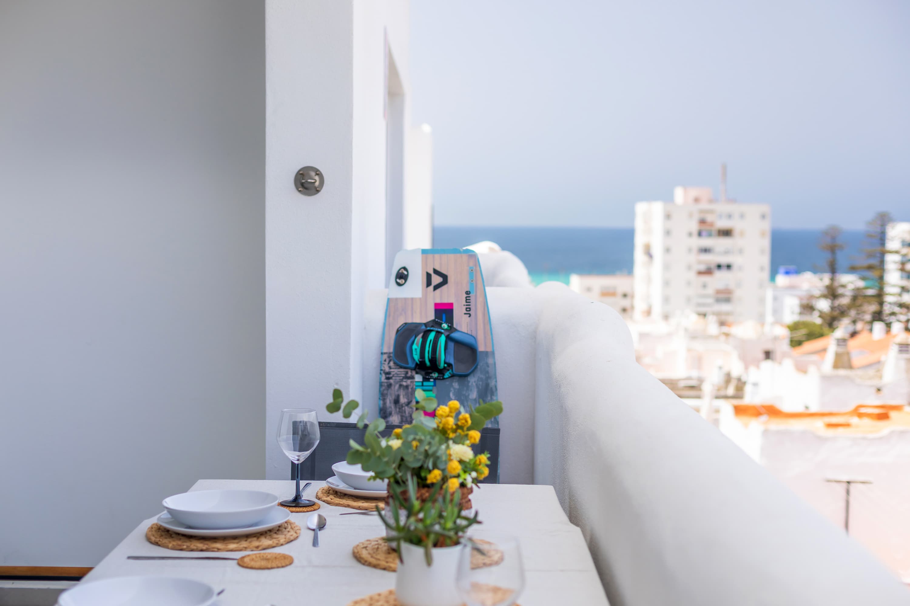 Downstairs Atlantic terrace dining table with a kiteboard leaning against the wall and the Atlantic in the background