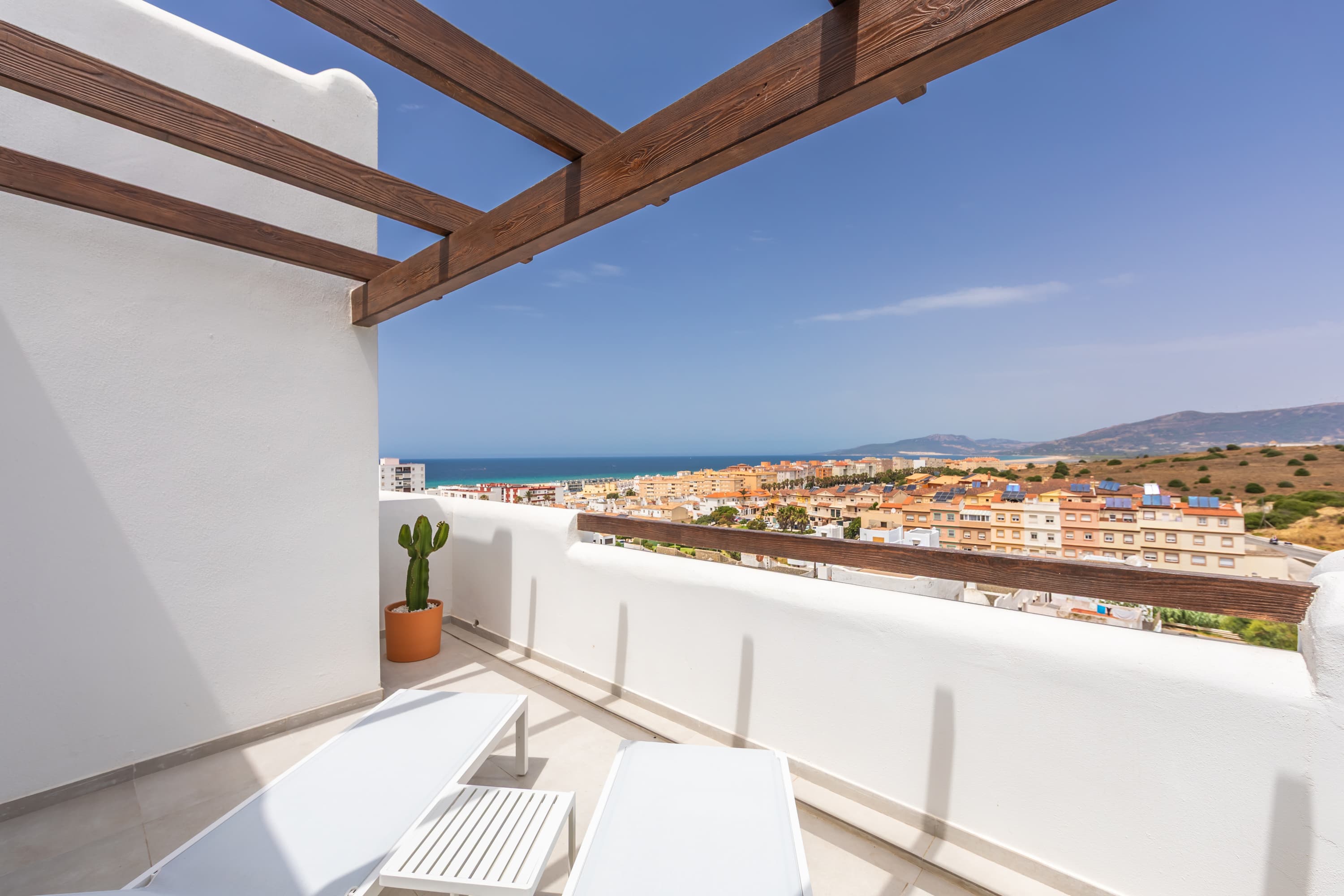 White sun loungers under the wooden pergola on the upstairs Atlantic terrace